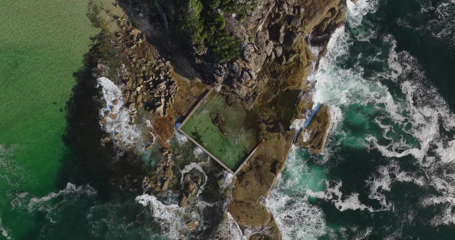 Aerial view of a natural pool surrounded by rocks and the sea