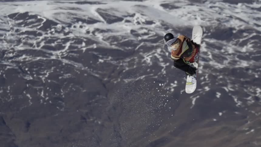 A snowboarder ascends a jump and does a trick