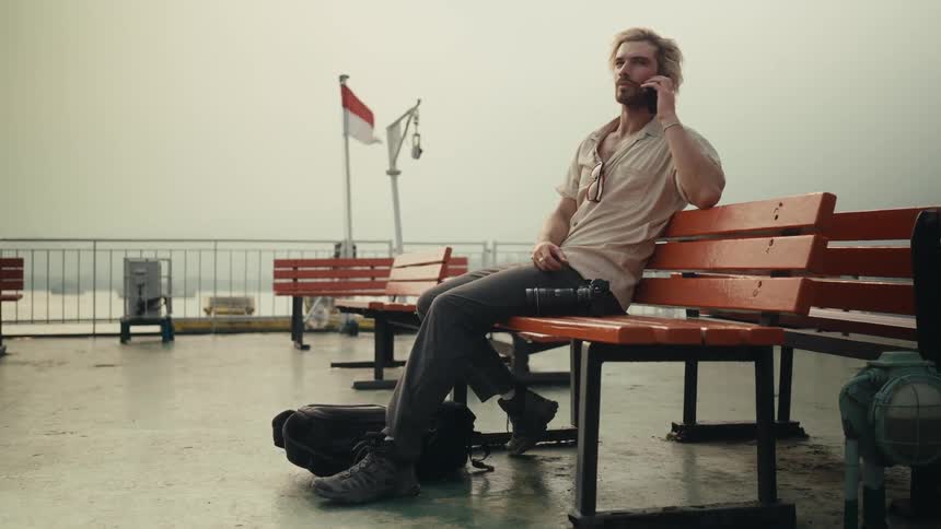 Man sitting on a bench answering a phone call