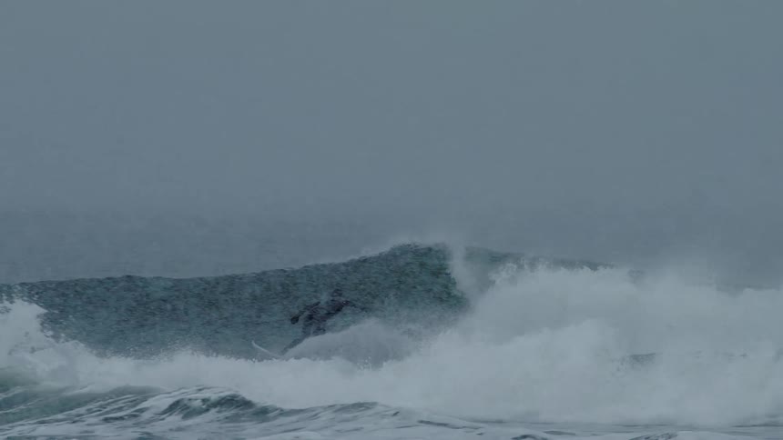 Man surfing on strong ocean waves during a rainstorm