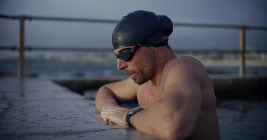 A swimmer comes out of the water and rests on the ledge