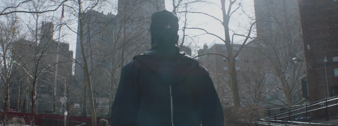 A man is walking towards some tall buildings