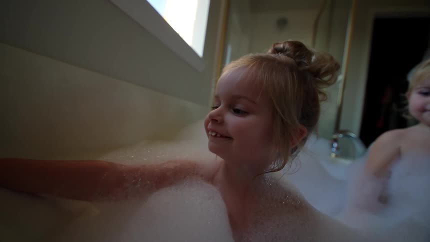 Girls taking a bubble bat in the bathtub at home
