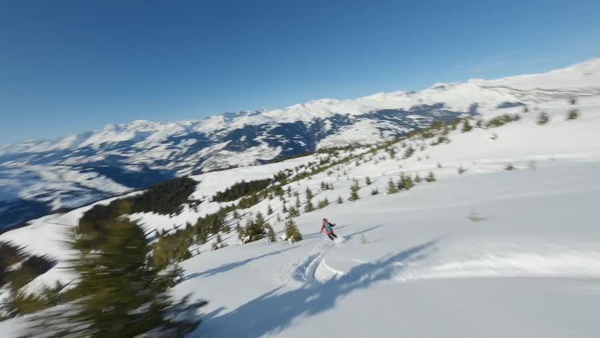Skier skis down a snowy slope covered in scattered conifers on a winter day in Switzerland