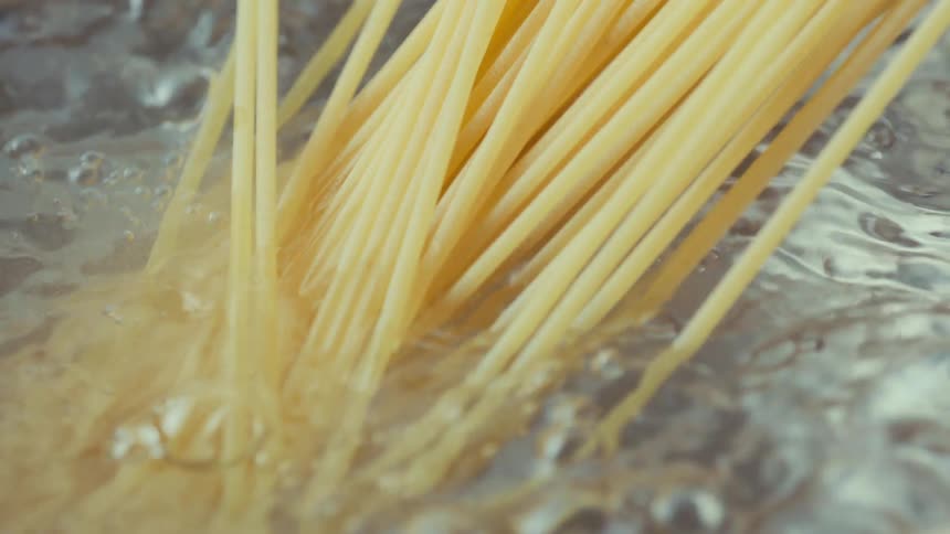 Spaghetti being added to a pot of boiling water