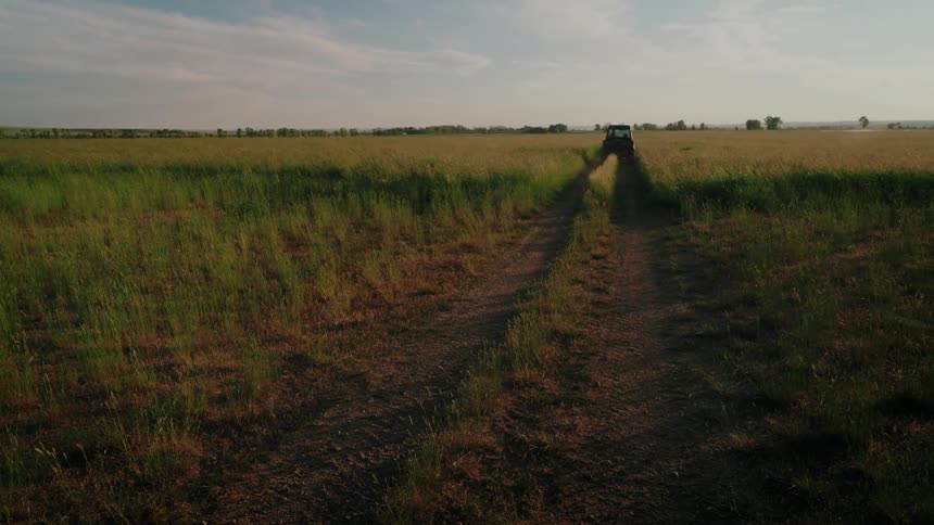 Small farm truck driving along a track in a green field
