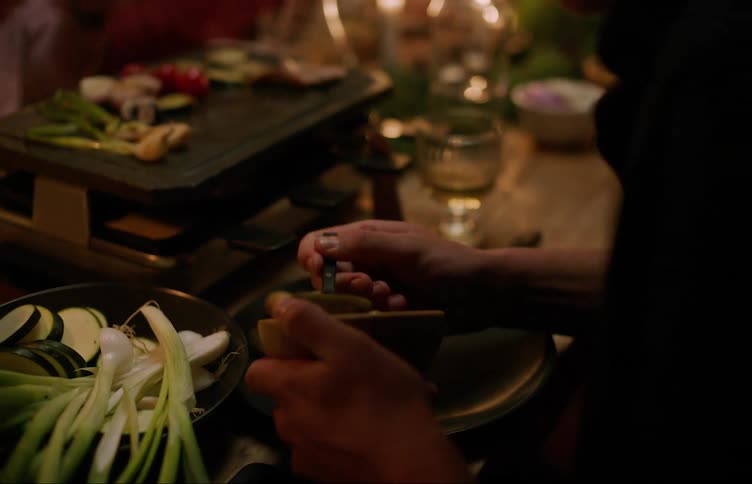 Person holding a bowl and serving himself at a table decorated with candles