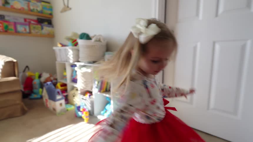 Litte girl in dress with a red tutu twirling in her bedroom