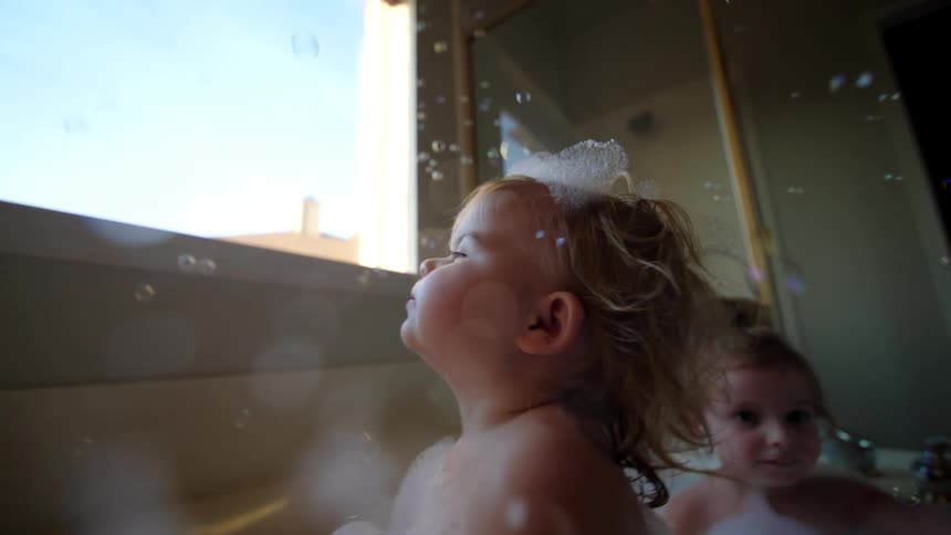 Two little girls in a bathtub with soap bubbles and foam