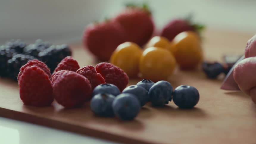 Hand with a knife chopping blueberries