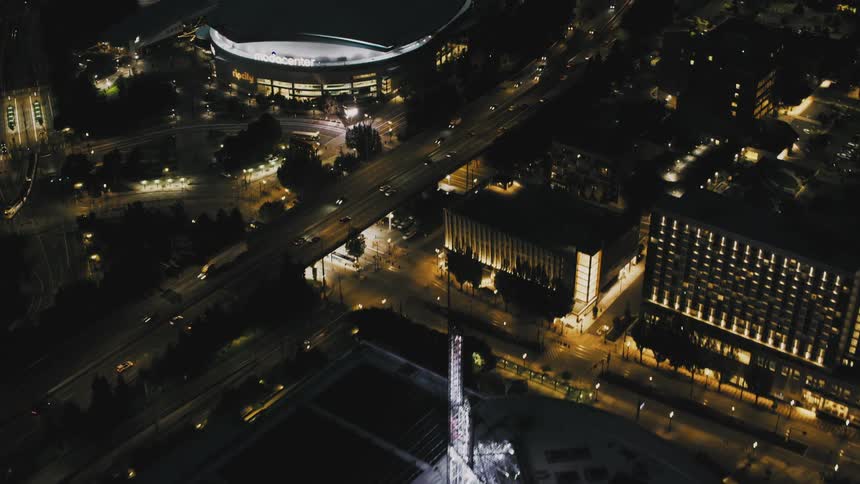 Aerial panorama of a metropolis at night and an illuminated stadium