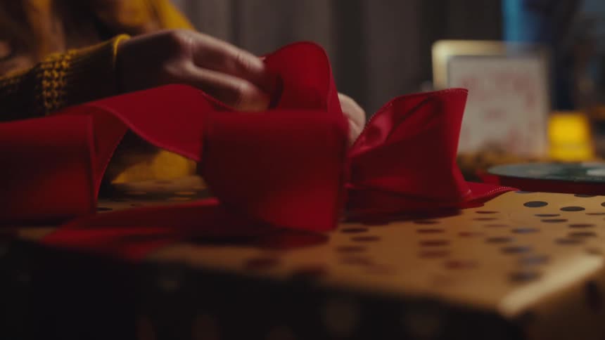 A woman ties a bow on the present