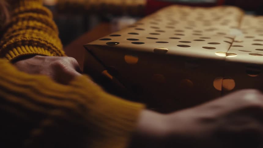A person is wrapping a gift and taping it