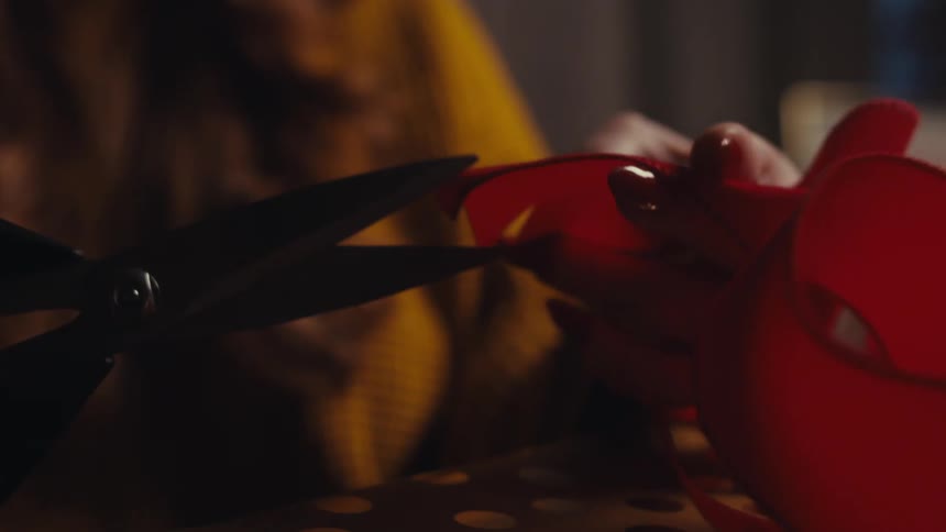 Close up of a person cutting the ends of a large red ribbon