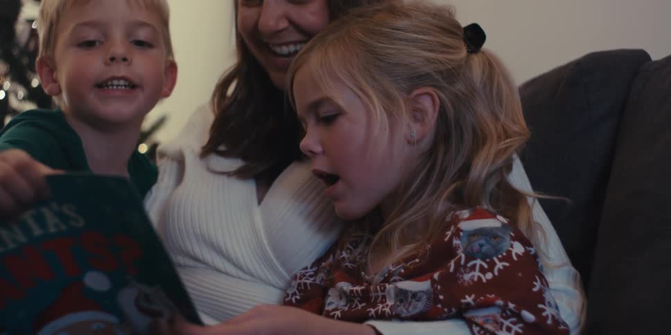 Mother sitting reading a book to her two children
