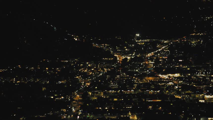 An aerial view of a city at night illuminated with a warm glow from countless streetlights and buildings