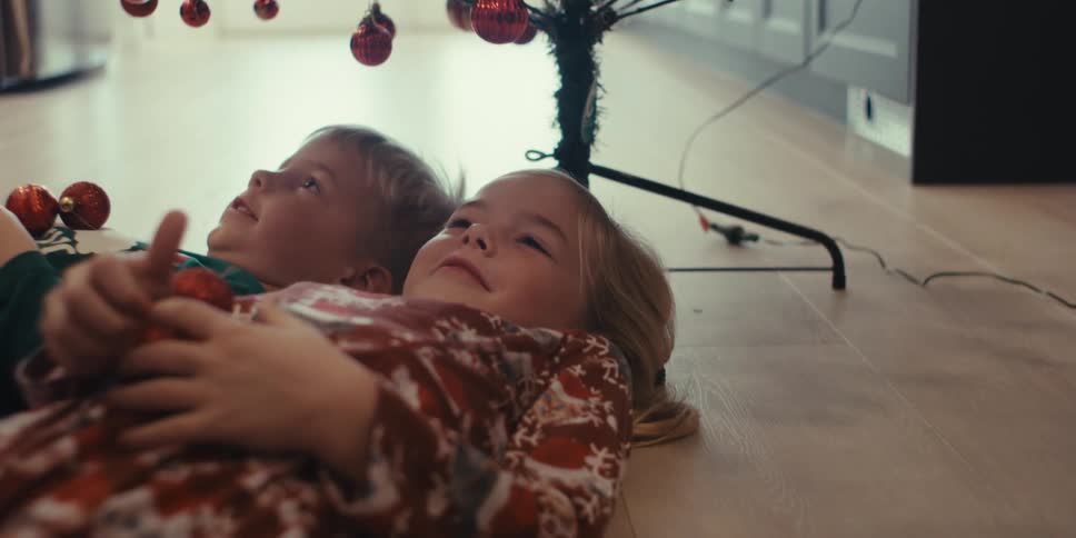 Two small children lying under a christmas tree