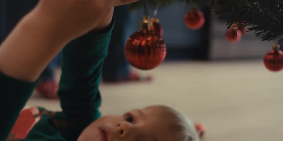 A clip of a kid fixing an ornament on a christmas tree