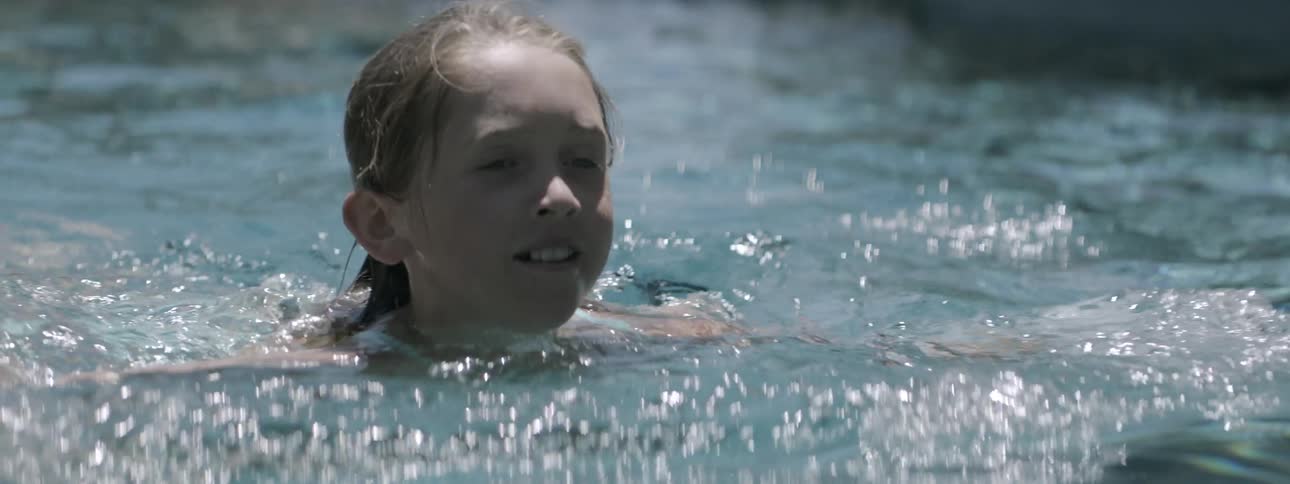 A girl is swimming in a pool on a sunny day