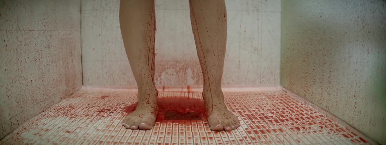 A person is showering with blood pouring off them