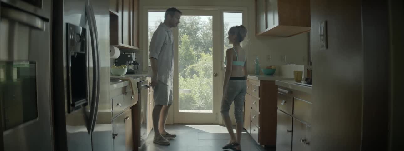 A man puts dishes away in a dishwasher then walks outside with a kid