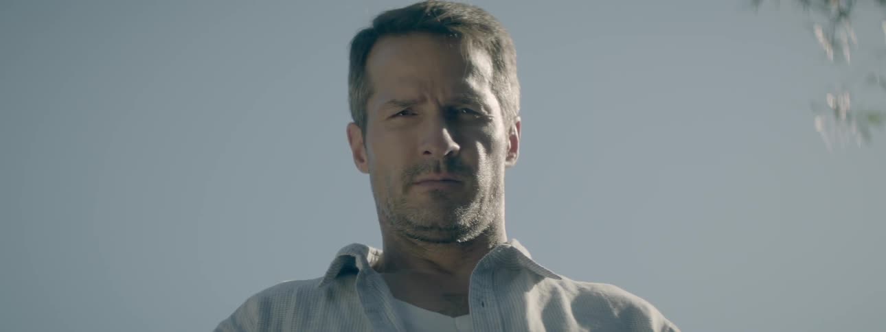 Man looking sternly down into the camera on a clear day
