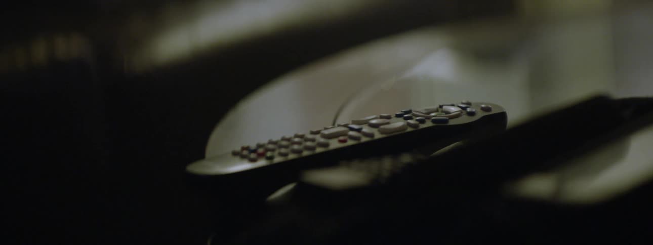 A man picks up the remote control off a table