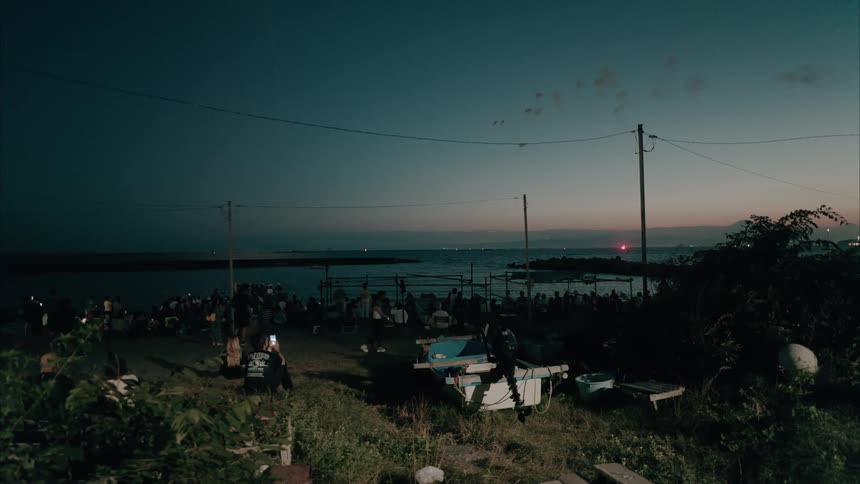A crowd watches the fireworks at sunset