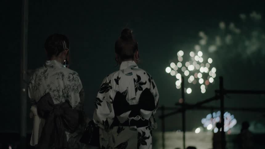 People standing along the coast watching fireworks