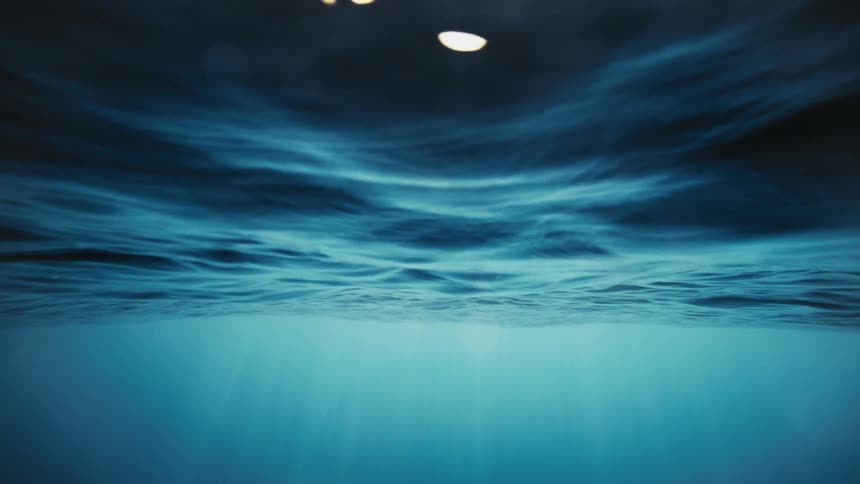 Random pale areas of light appear through the surface over the ocean depths