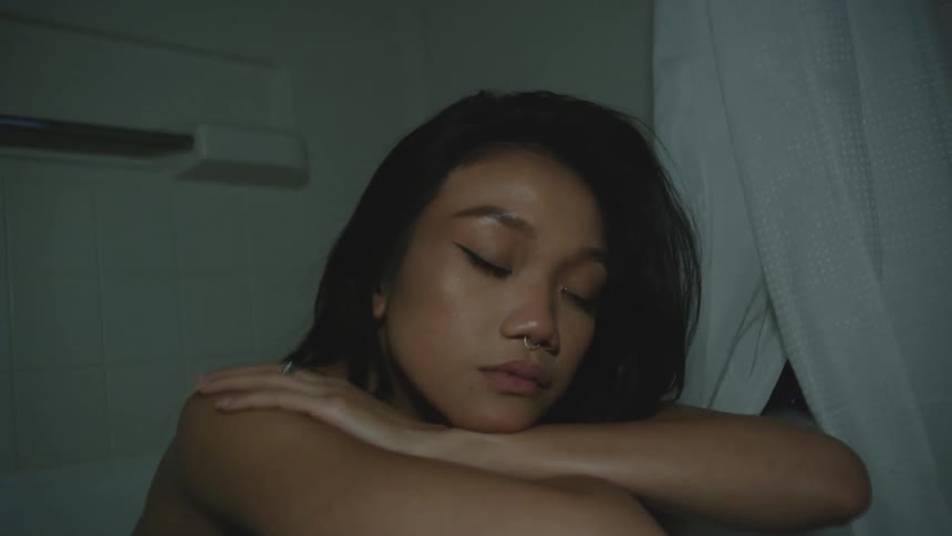 Young model wearing a blue blouse inside a bathtub