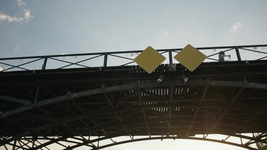 People walking silhouetted on a bridge the camera moves under the bridge to show its intricate metalwork