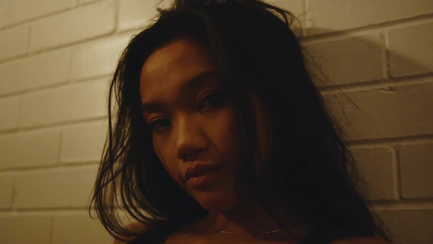 A woman is leaning against the brick wall