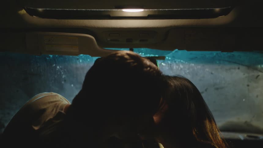 Couple inside the car kissing on a rainy night