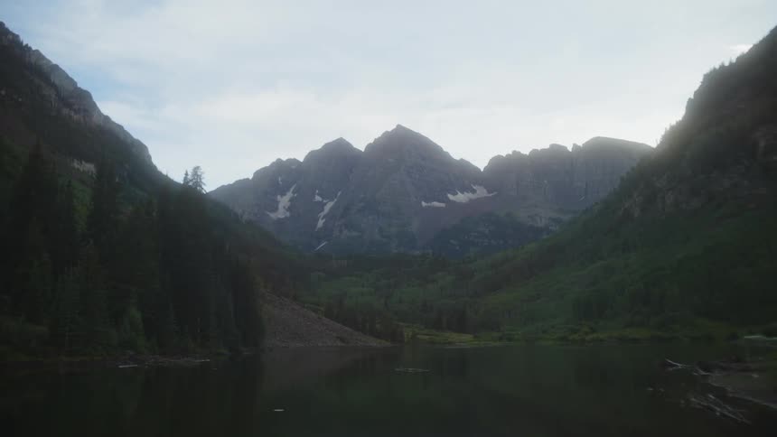 A tranquil lake nestled amidst a valley with a majestic mountain range rising in the distance