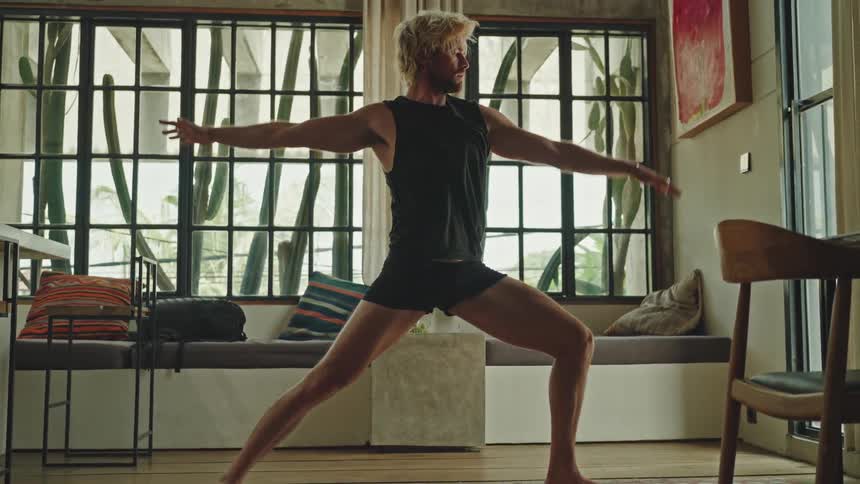 Man in a living room stretching his body in a yoga position