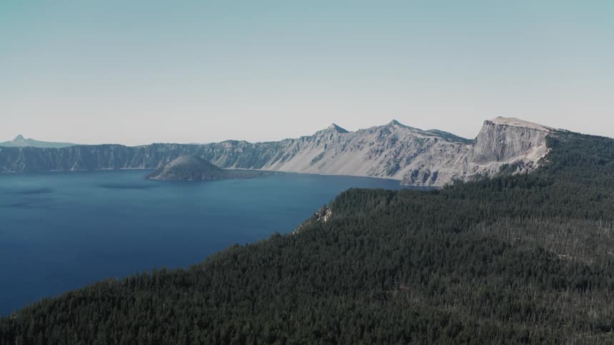 A large lake is surrounded by forest covered cliffs