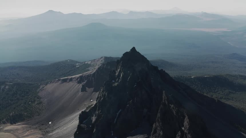 Mountain with a high peak and mountains in the distance under a hazy sky