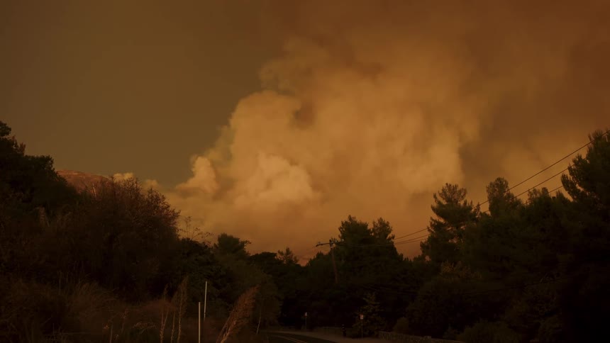 Smoke rises over a forested mountain