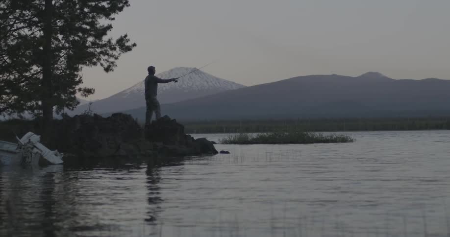 A fisherman casts his line into the water