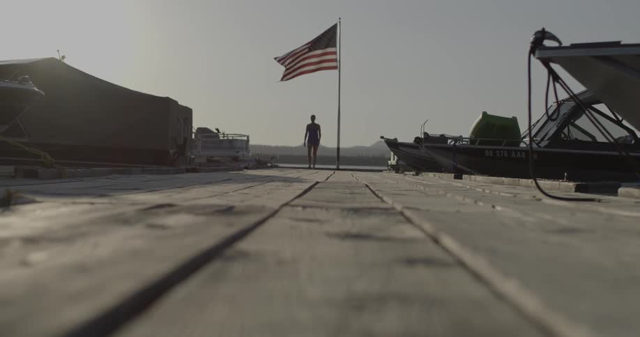 Person walking with a large american flag behind them on a clear day
