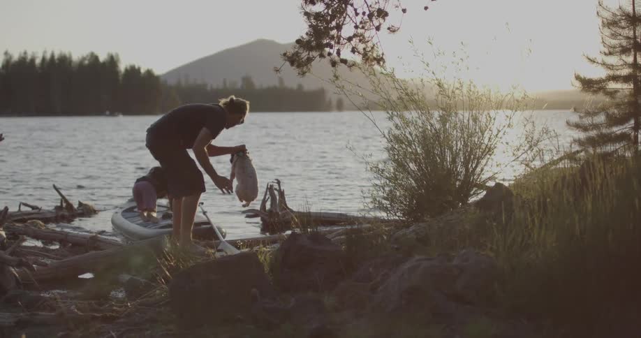 A man is lifting a dog into a kayak