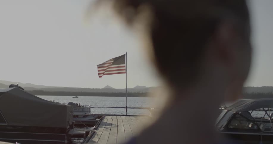 A view of the american flag waving behind a woman's head