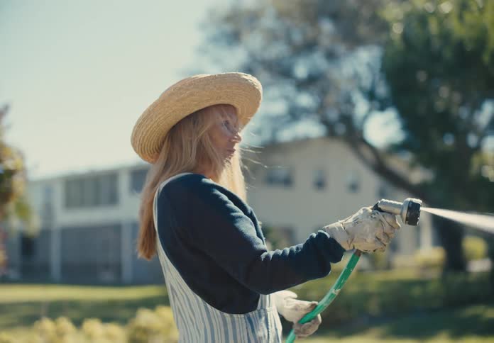A woman is watering the garden by her home