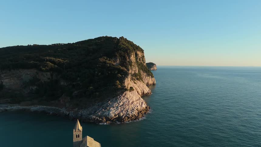 Seagulls fly near the promontory with the church of san pietro in portovenere on the rocks overlooking the sea