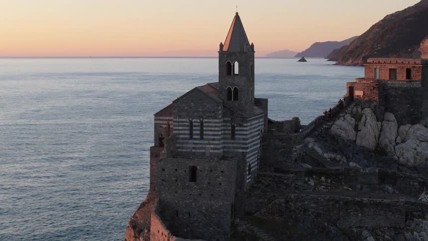 Coastal landscape at dusk with a pointed bell tower located on a cliff by the sea