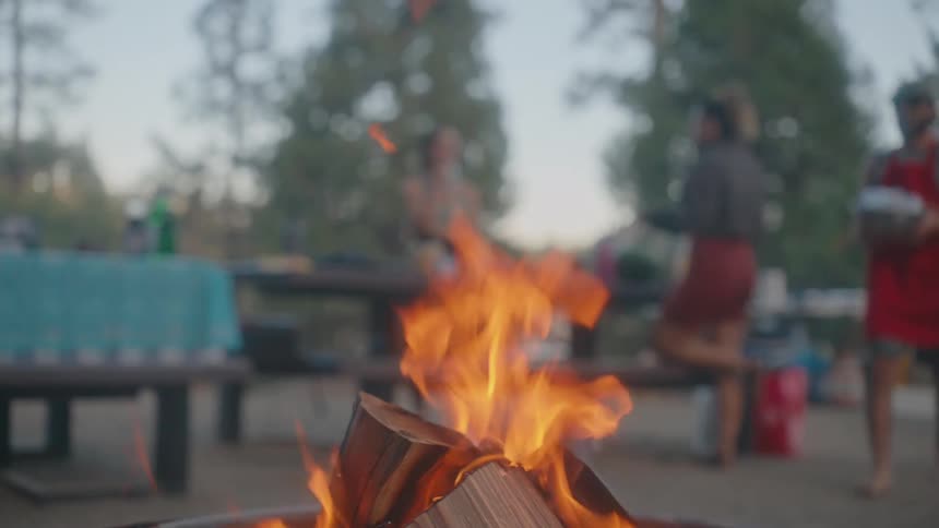 Close up of a bonfire and people walking in the background