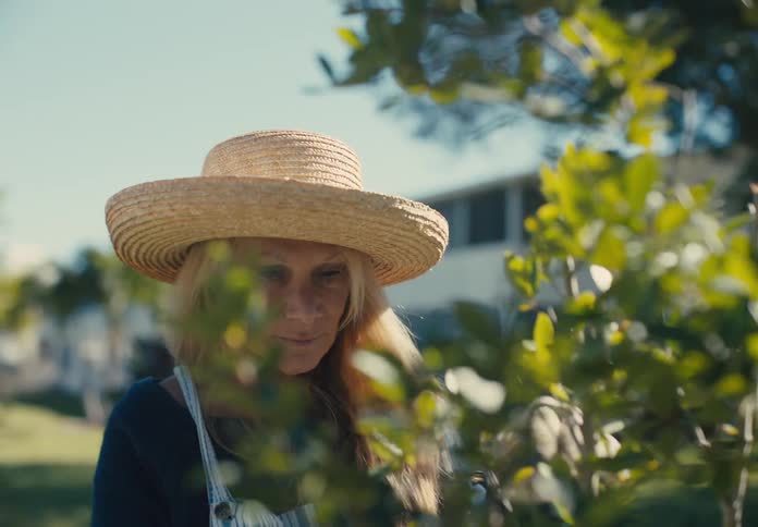 A blonde woman prunes a tree