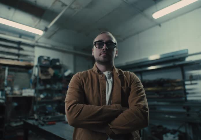 Man with glasses and arms crossed in a workshop