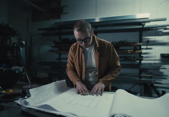 Man in a workshop working with cardboards of industrial drawings and projects on a table